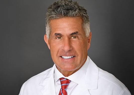 Professional headshot of orthopedic surgeon Dr. Kevin Alan McCracken, MD, smiling in white lab coat.