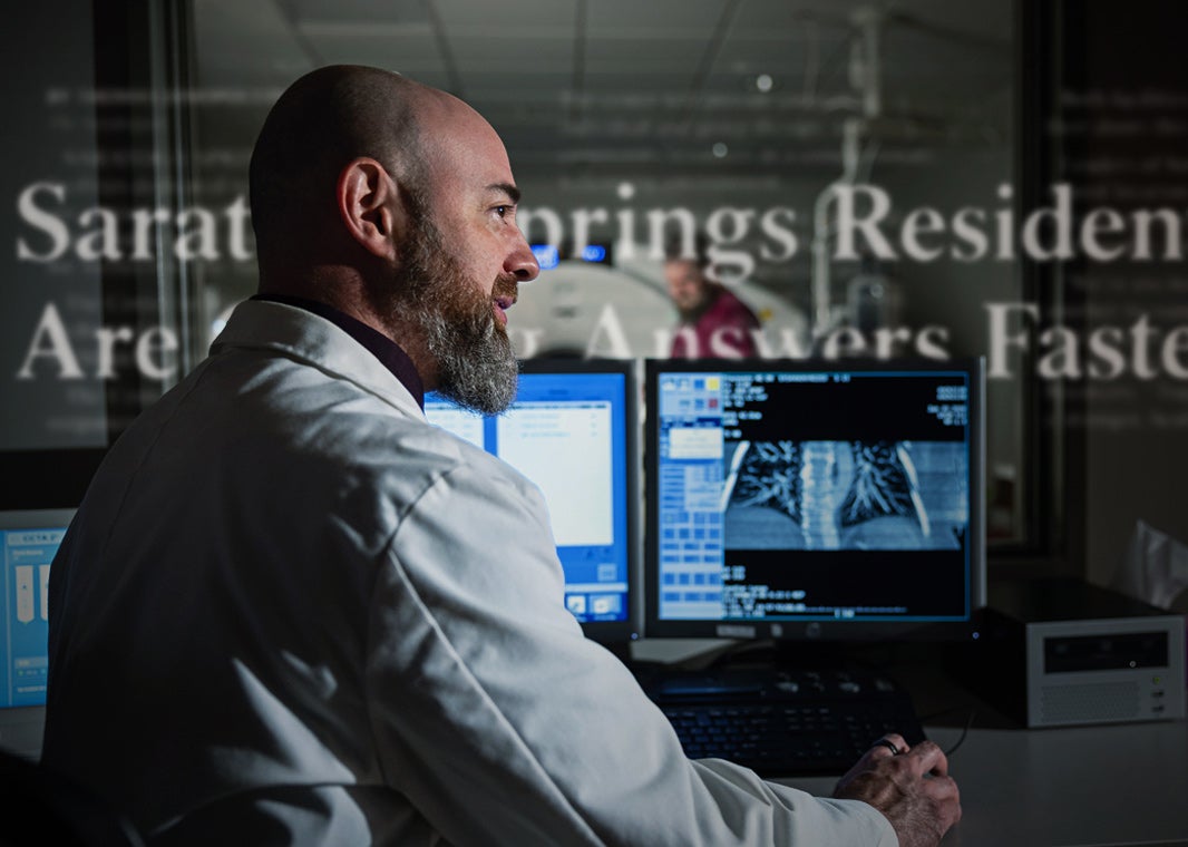 Dr. Douglas Walled, board-certified diagnostic radiologist, looks off-camera while seated before a trio of medical monitors.