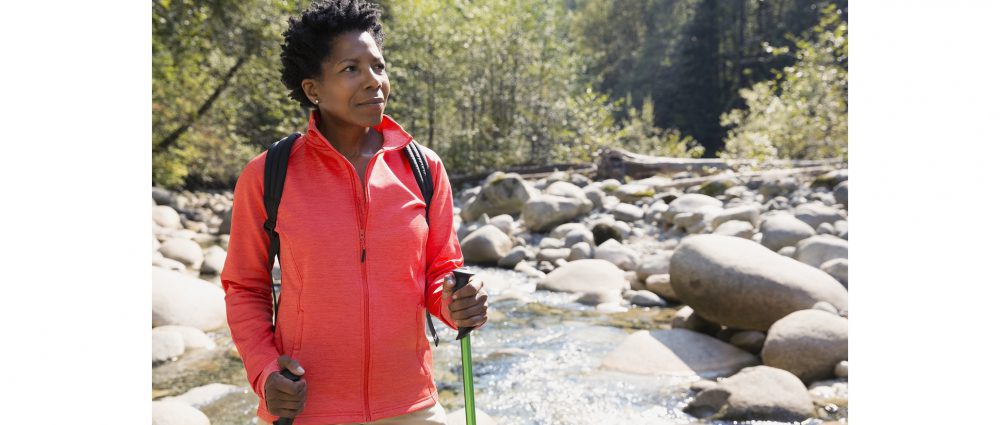 Woman with hiking poles in sunny woods