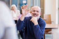 Senior man raising his hand to ask a question at an educational event.