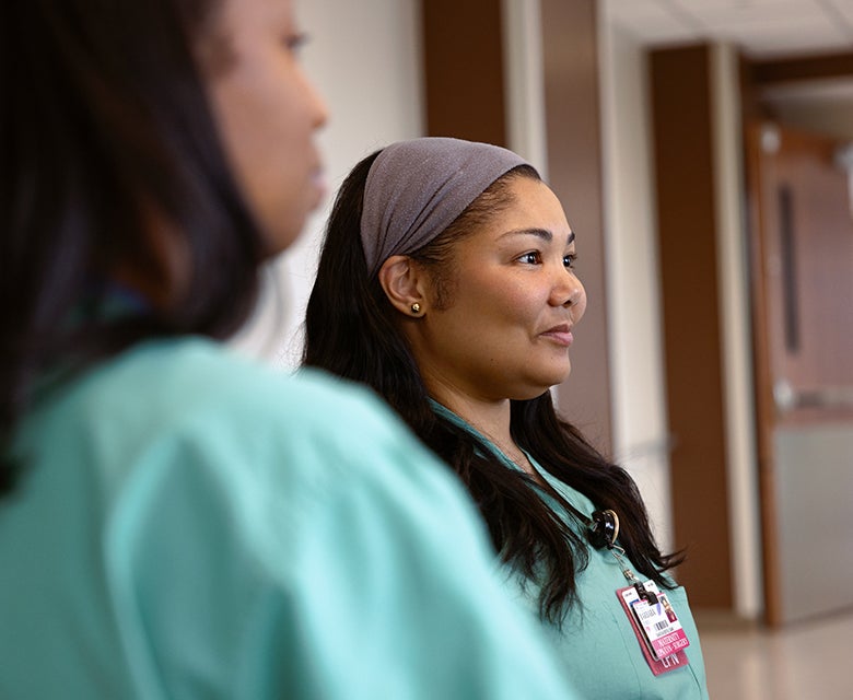 Closeup of a female L&D nurse in scrubs listening attentively during a team meet ahead of providing excellent maternity care.