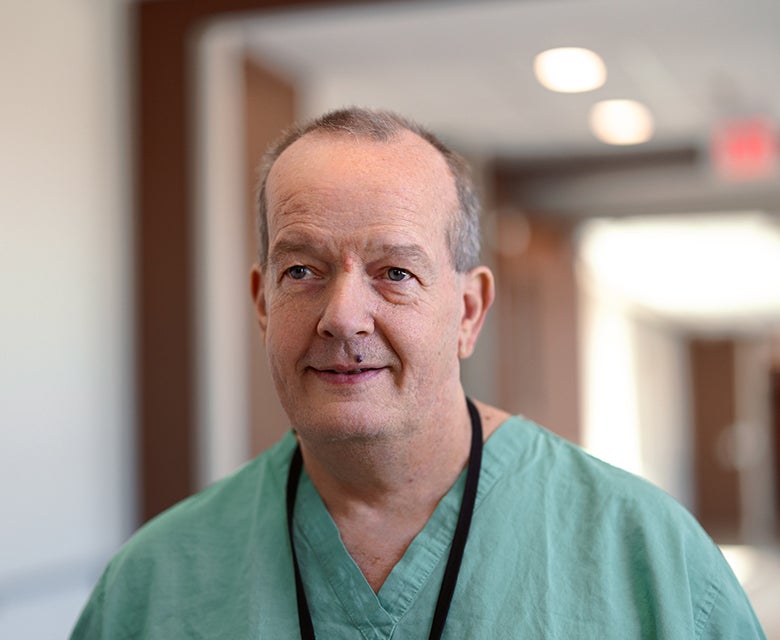 Closeup of Dr. Philip Clements walking the hospital hallways on his way to meet with diverse OBGYN patients and families.
